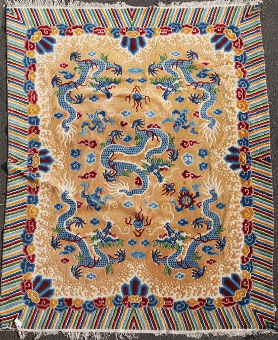 A Chinese carpet, the apricot field with five indigo dragons with a polychrome banded border, 10ft by 8ft 1in.